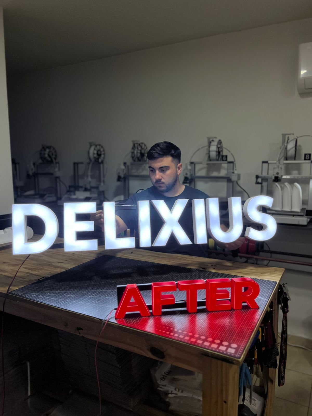 Cartel LED Delixius sostenido por Lázaro en el taller